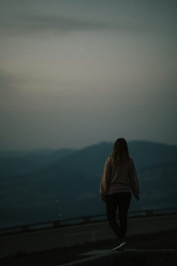 a woman standing on top of a hill looking at the sky